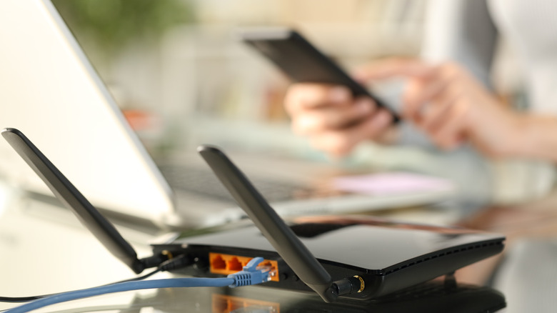 tech news router on a table with a woman using her phone in the background