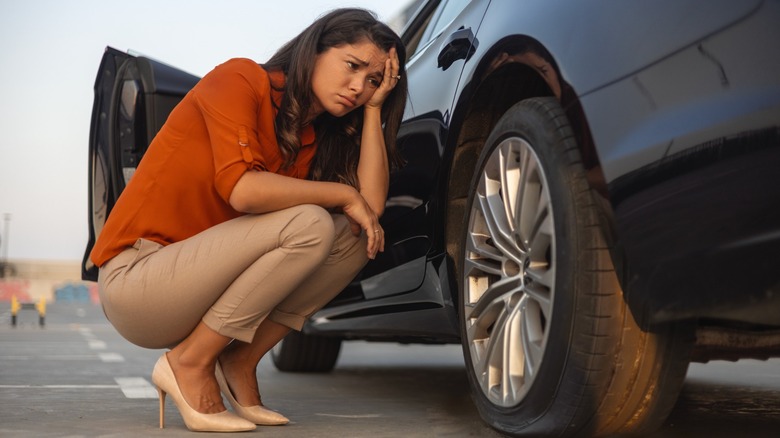 A woman looking sadly at her tire