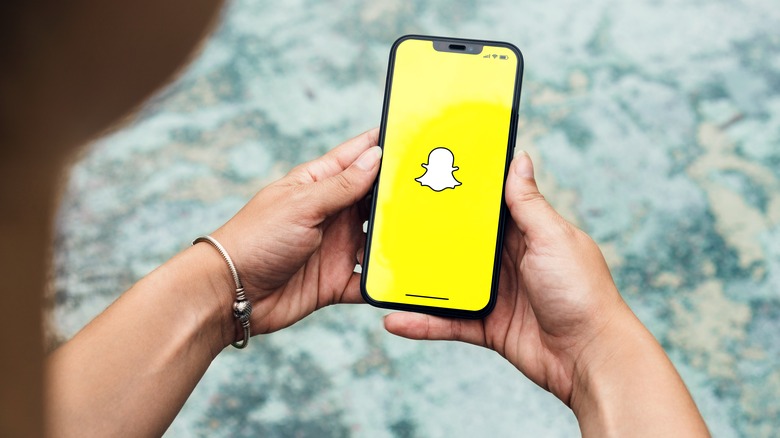 hands holding iPhone with Snapchat logo