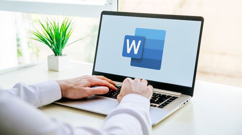 Man using a laptop computer displaying logo of Microsoft Word on the screen