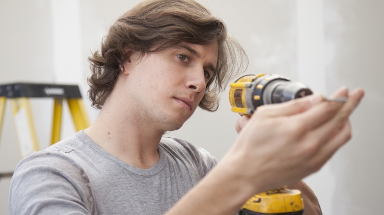 A person inspecting a yellow power drill