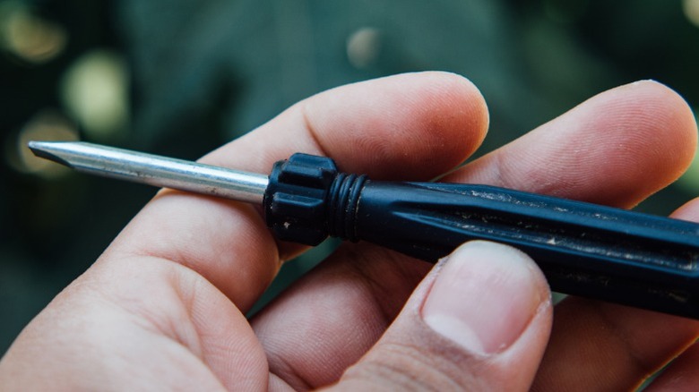 A closeup image of a person holding a used screwdriver