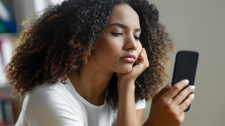 pensive woman reading iPhone messages