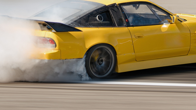 Yellow sports car speeding with smoke coming out from behind