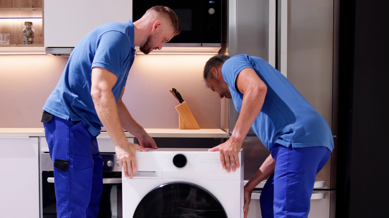 Two men moving a washer into place