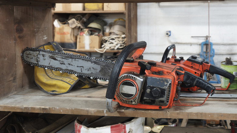 An old chainsaw with a tarnished blade on a wooden bench in a workshop