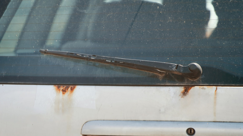 A wiper on the back of a rusty vehicle