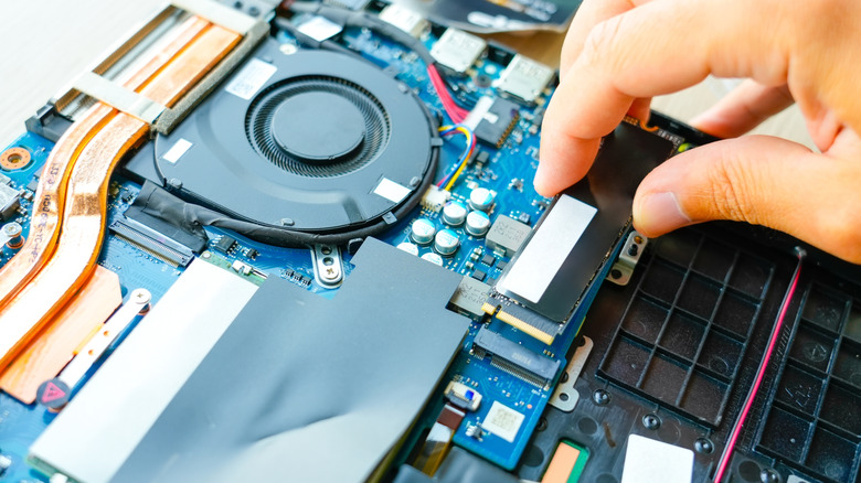 Person installing an SSD inside a laptop