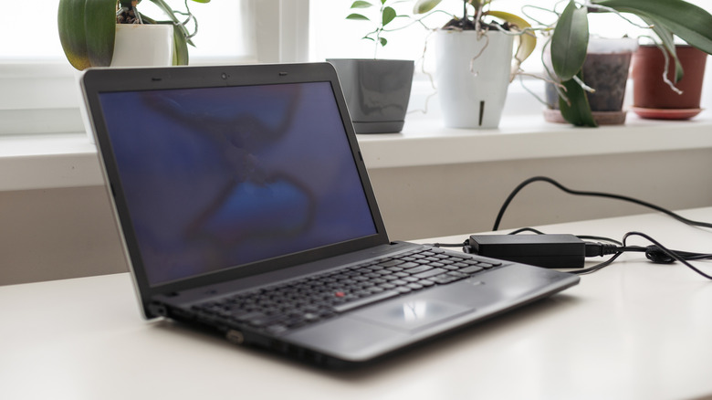 A laptop being charged on top of a desk