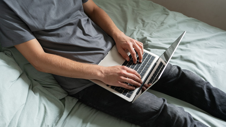 A person using a laptop on his legs