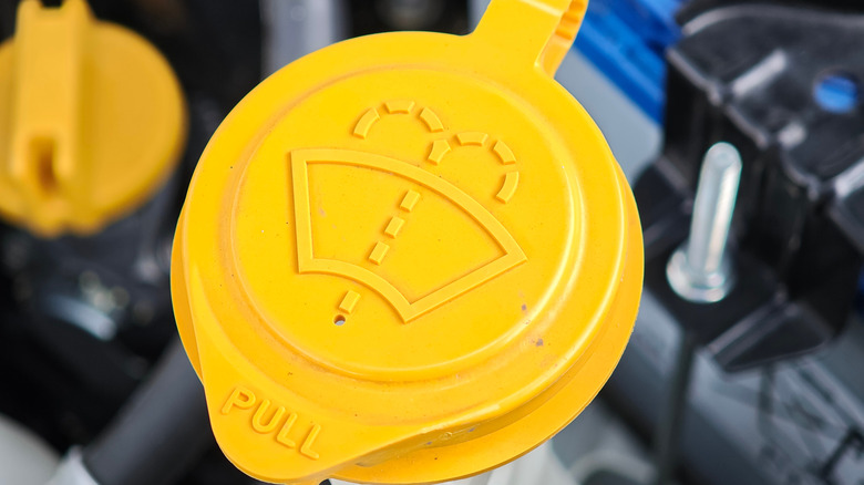 A yellow cap of a windshield washer fluid reservoir.
