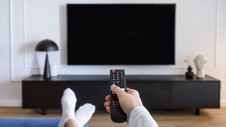 A person turning on a TV using a remote