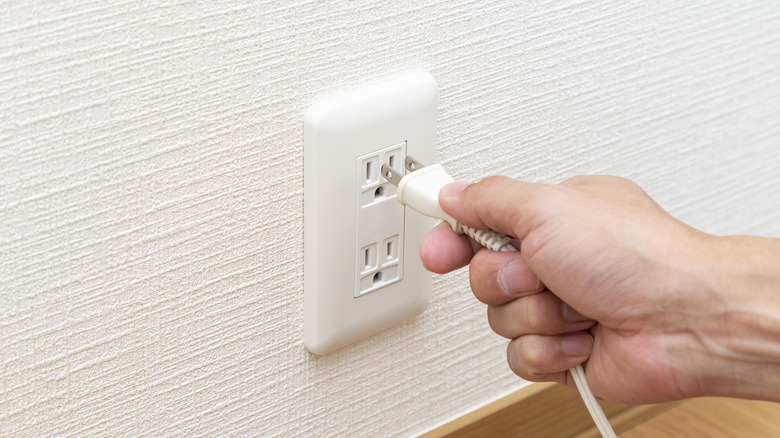 A plug being unplugged from a socket