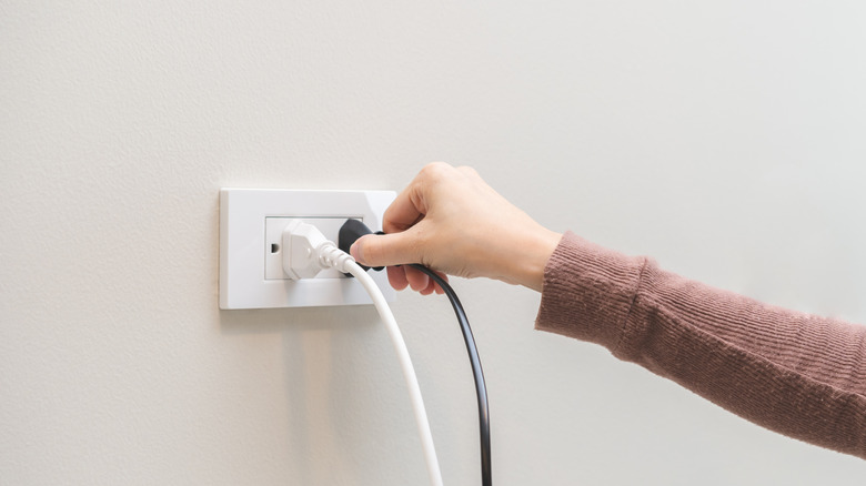 A person unplugging a plug from a socket