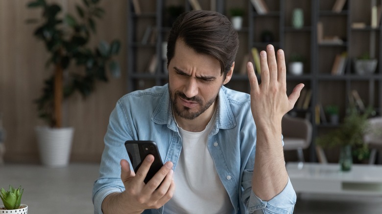 man frustrated while using smartphone