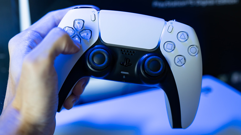 one hand holding a white PS5 DualSense controller