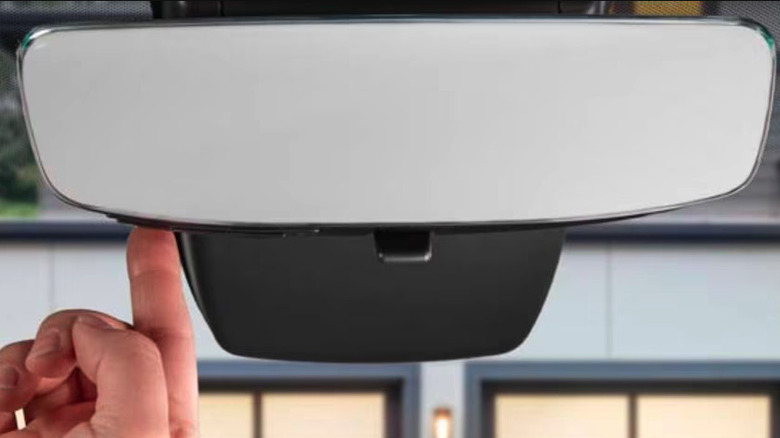 Person pressing button on rearview mirror to open garage door