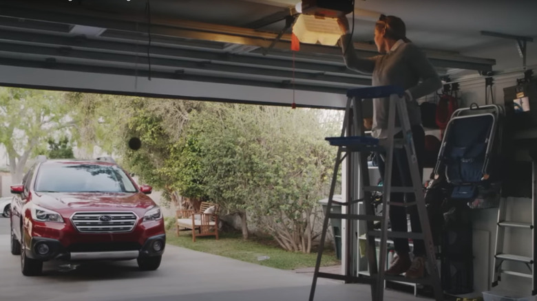 Woman pressing learn button on garage door opener to pair with homelink in Subaru