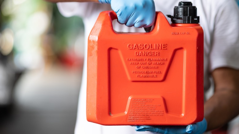 person holding red gas can