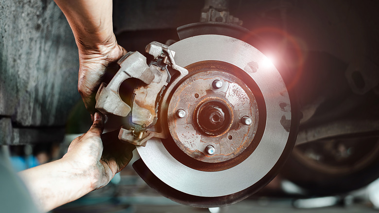 Close-up of a mechanic's hands working on a car's disc brake system, highlighting maintenance and repair