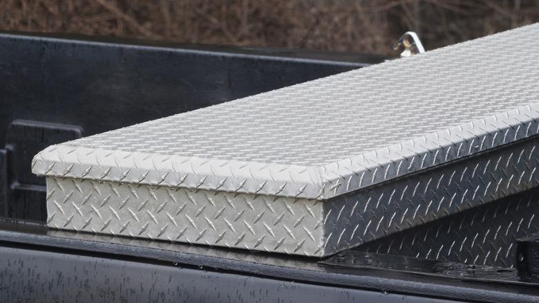 A metal crossbed toolbox across the bed of a black pickup truck.
