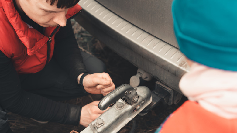 A man connecting a trailer hitch to his vehicle