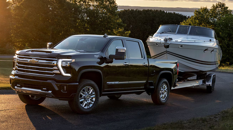 2024 Chevrolet Silverado 3500 High Country HD hauling a small boat on a double axle trailer