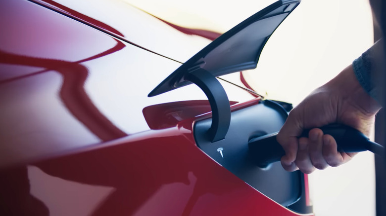Red Tesla Model 3 plugged into an EV charger