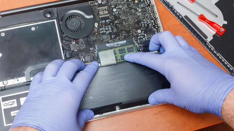 Engineer installing a new battery in a MacBook