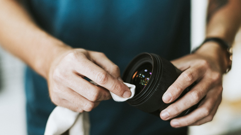 person cleaning a camera lens