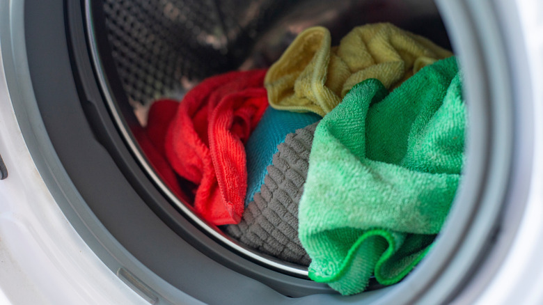 Several microfiber cloths in different colors sitting inside the metal drum of a dryer