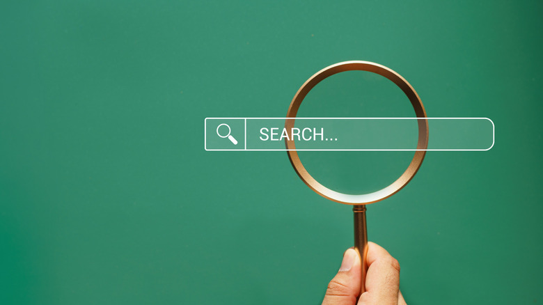 A hand holding a magnifying glass.