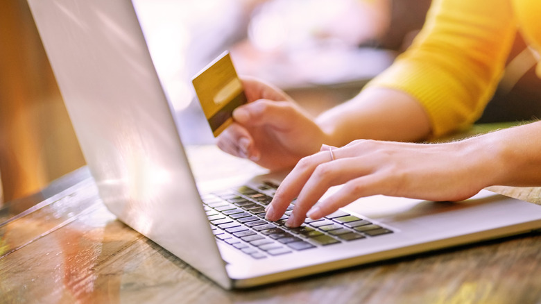 A woman with a credit card in her hand using a laptop.