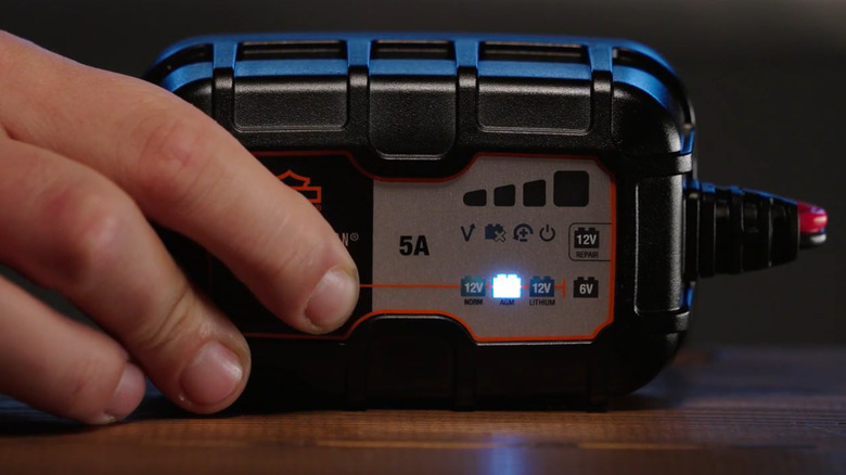 Hand pushing the mode button on Harley-Davidson 5A battery charger