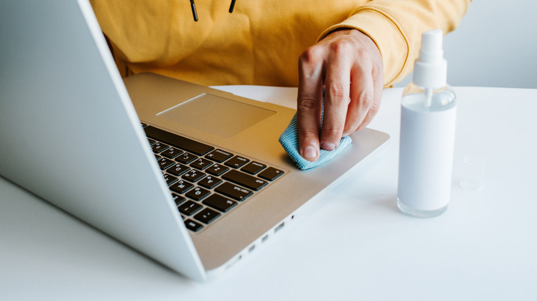 person cleaning a MacBook