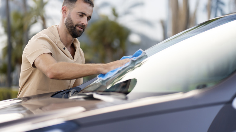 Man wiping the car's windshield with blue cloth