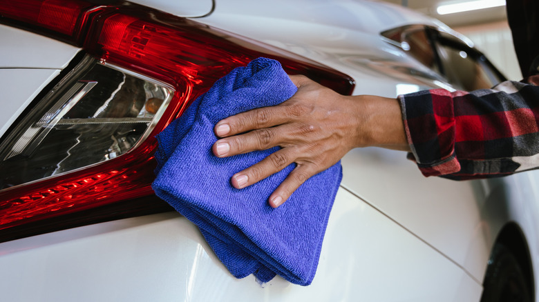 Person cleaning a white Honda Civic with microfiber cloth