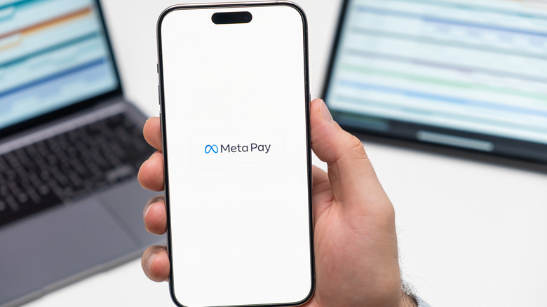 Person holding smartphone with Meta Pay logo on screen