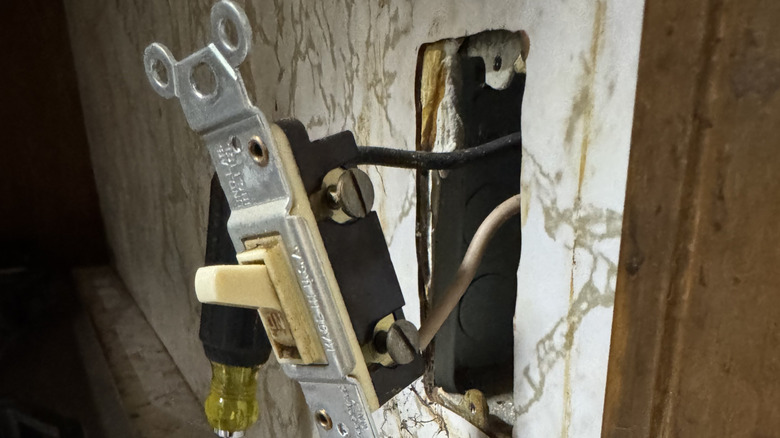 An old light switch with wires entering the back of the switch body