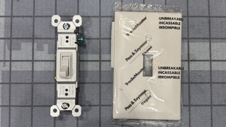 A picture of a brand new white light switch and white face plate for the switch