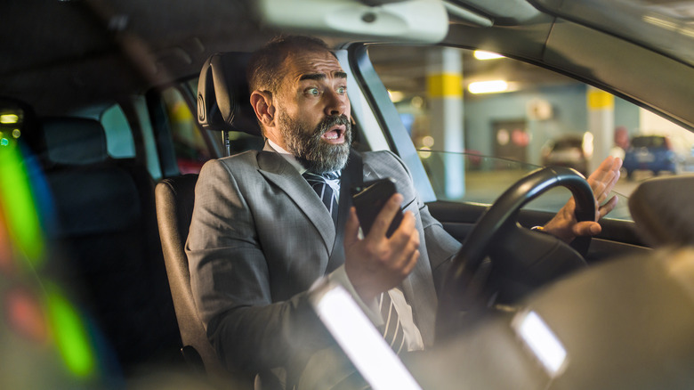 scared man driving holding phone