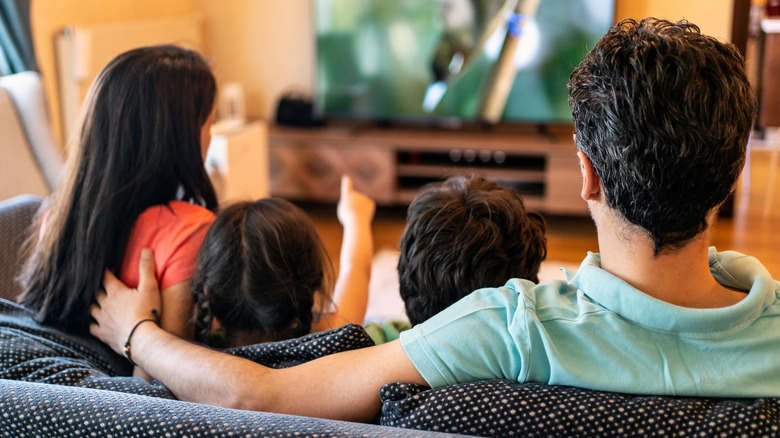 Family watching movie on projector with snacks