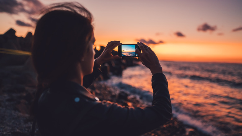 person taking picture of sunset