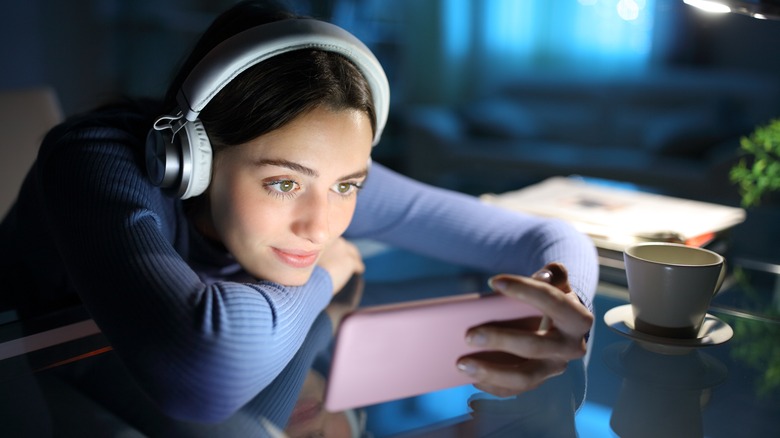 Woman wearing headphones watches smartphone