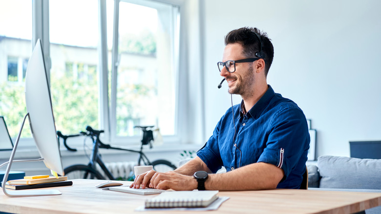 Man smiles at computer on desk