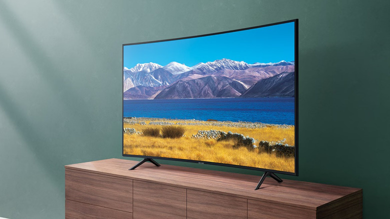 Curved TV displaying scenery while on top of a TV stand