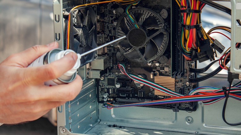 Man's uses compressed air to clean the insides of a computer