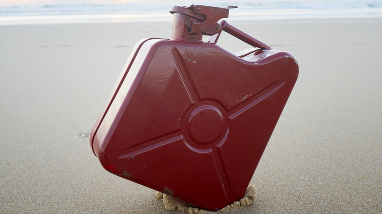 A red jerry can isolated on a beach.