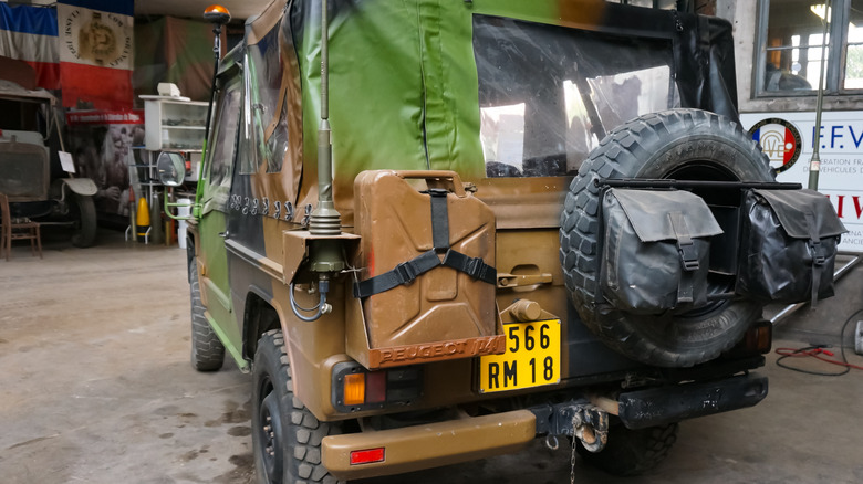 Metal jerry can mounted on the rear of a four-wheel-drive vehicle in military-style camouflage.