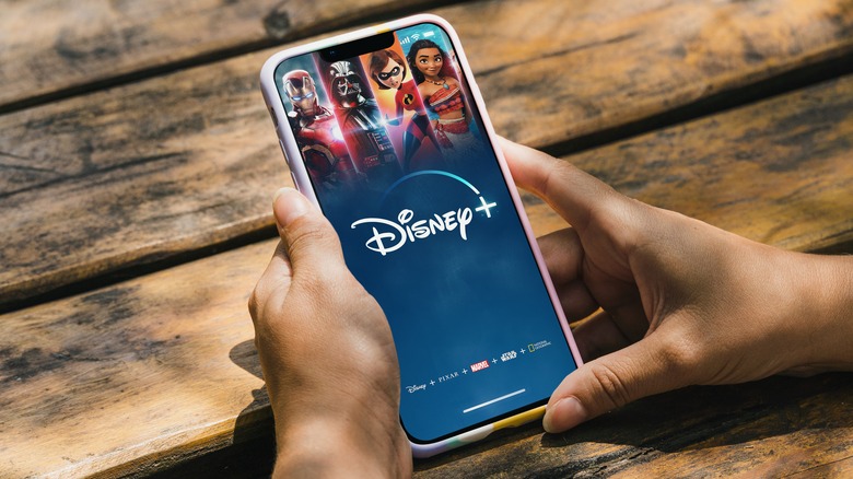 Hands holding smartphone displaying Disney+